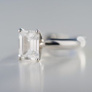 Nahaufnahme eines Silberrings mit einem klaren, rechteckigen Edelstein im Emerald-Schliff.