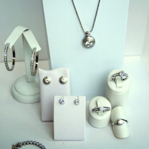 Ausstellung eines Sets aus silbernen Schmuckstücken mit funkelnden Steinen, darunter Halskette, Armband, Ohrringe und mehrere Ringe.